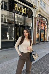 a lady in a beige sweater and a pair of brown pants